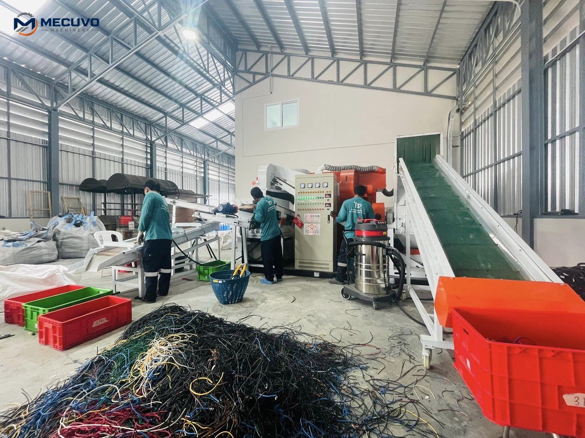 Workers preparing waste cable feed beside a copper granulator