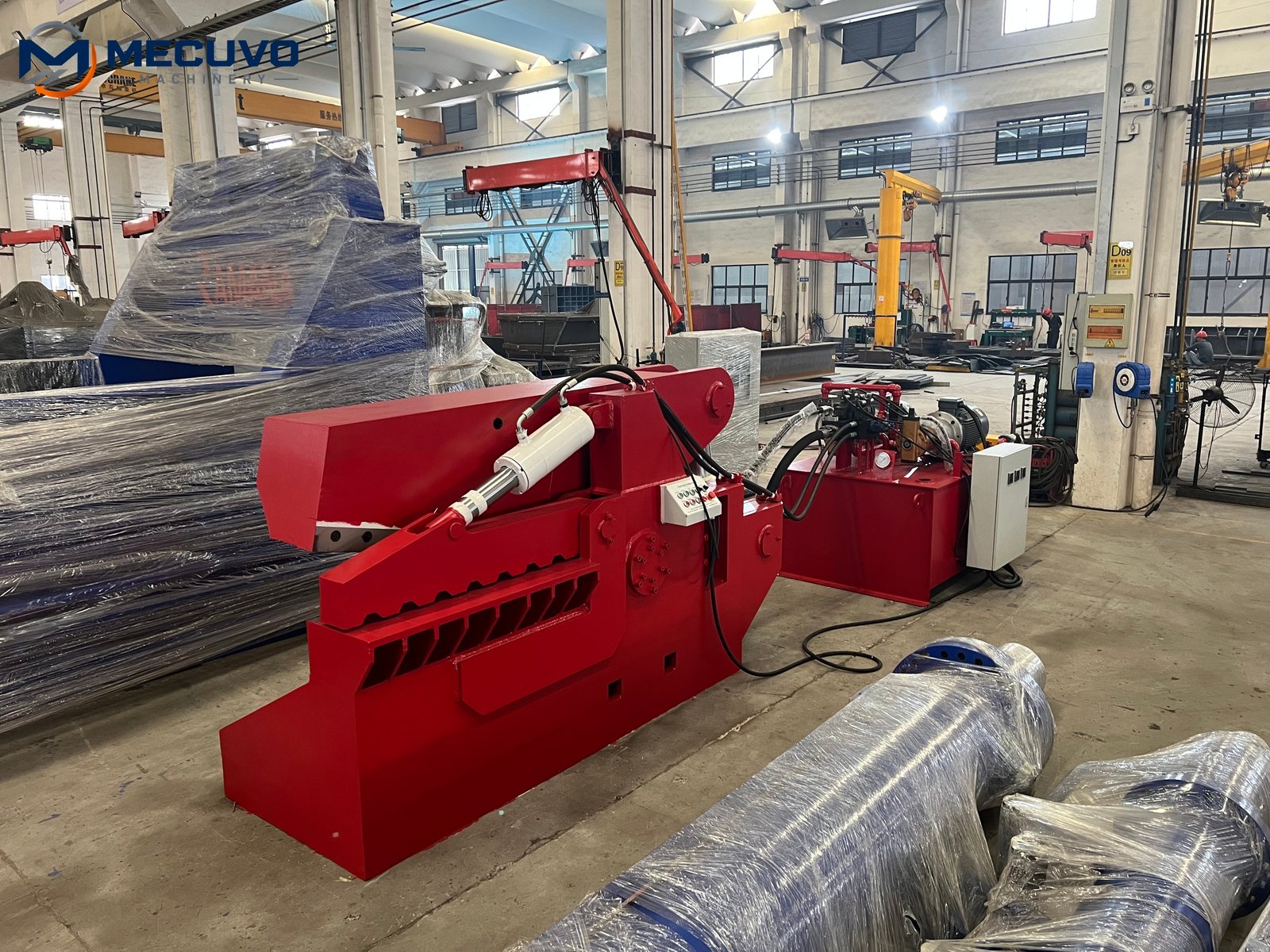 Alligator shear in a factory preparation area beside wrapped equipment Large hydraulic shear loaded at a container for shipment