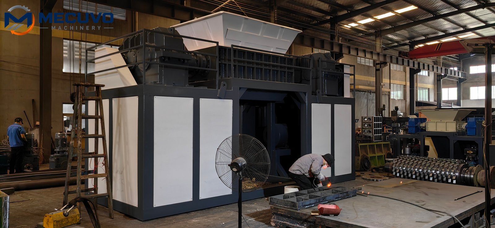 Personnel assembling an industrial shredder on the factory floor